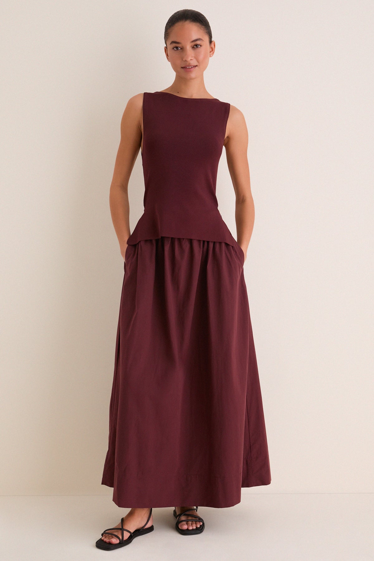 Woman in Dark Cherry Boatneck Mix Media Midi Dress with side pockets, styled effortlessly with black sandals for a classic, high-end look, perfect for fun day-to-night transitions.