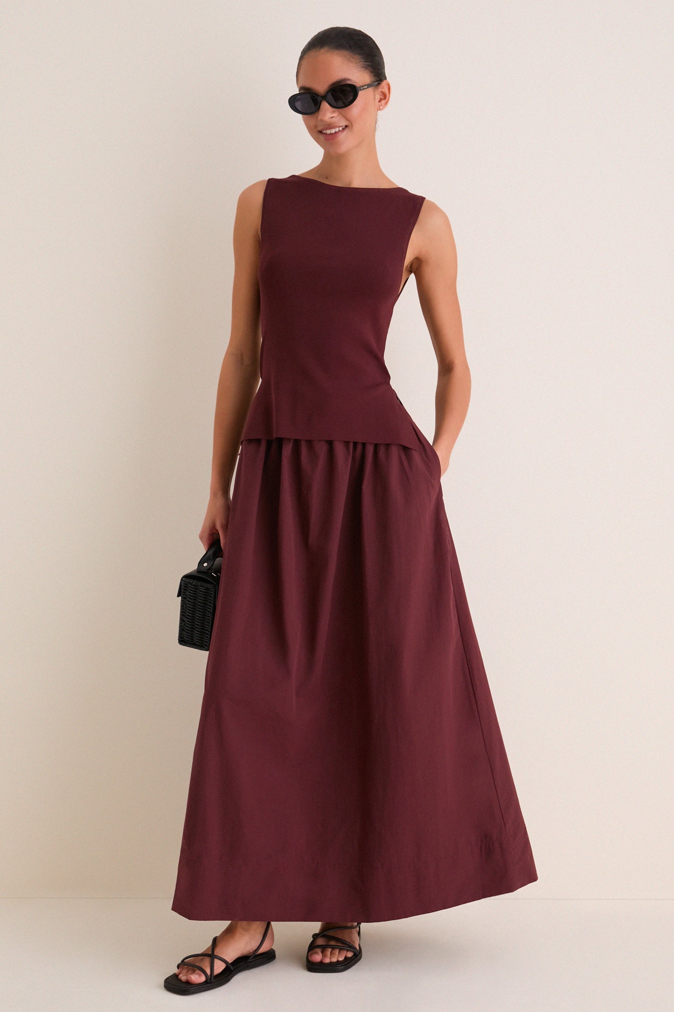 Model wearing Dark Cherry Boatneck Mix Media Midi Dress, showcasing a classic, effortless style with a streamlined silhouette, accessorized with black sunglasses and a woven handbag.