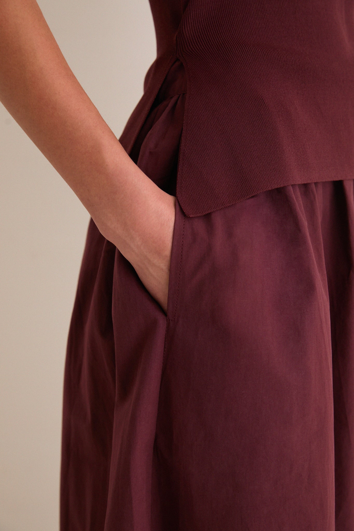 Close-up of hand in side pocket of the Dark Cherry Boatneck Mix Media Midi Dress, showcasing its classic, effortless design with a sleek silhouette and high-end texture contrast.
