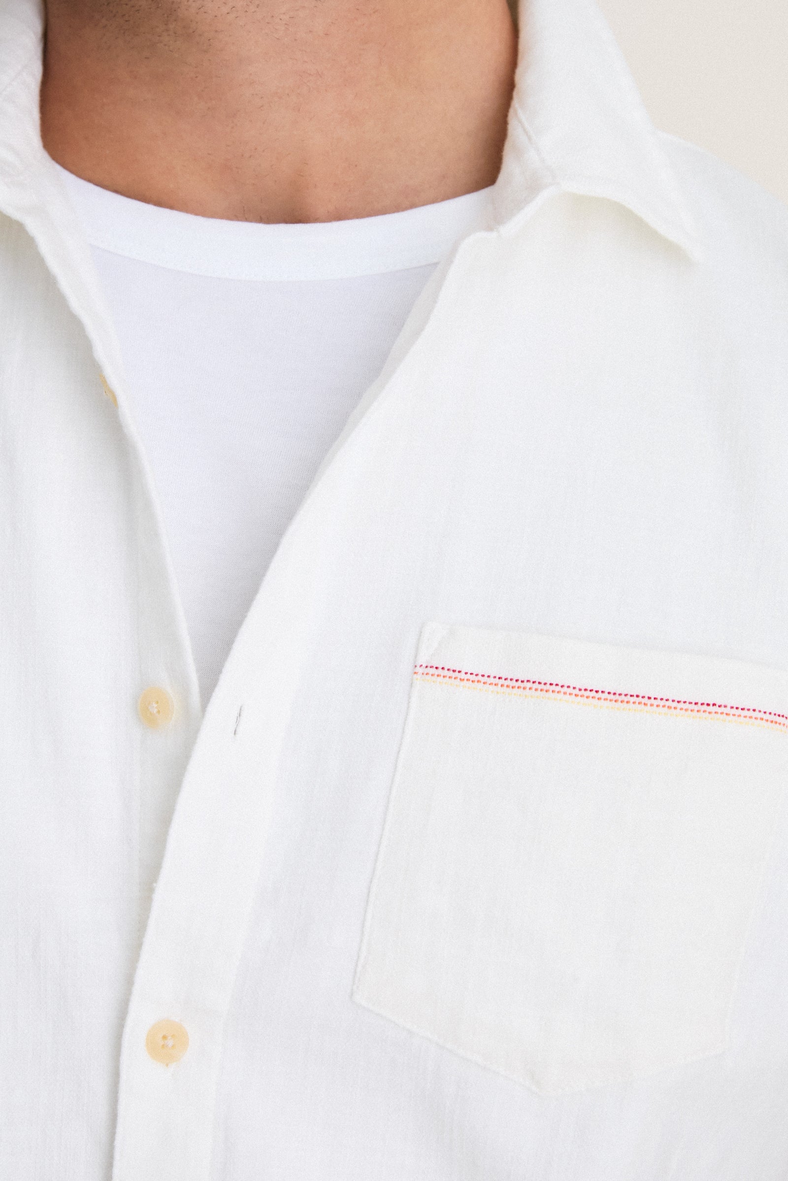 Classic White Stretch Selvage Shirt with red and yellow stitched pocket detail, worn over a white tee, embodies effortless, high-end style with added comfort and fun versatility.