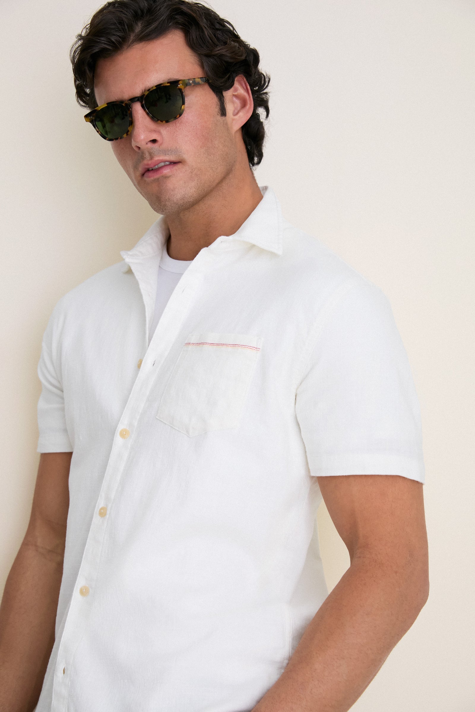 Young man in tortoiseshell sunglasses wearing the White Classic Stretch Selvage Shirt by Marine Layer, showcasing its classic, effortless style and high-end comfort.