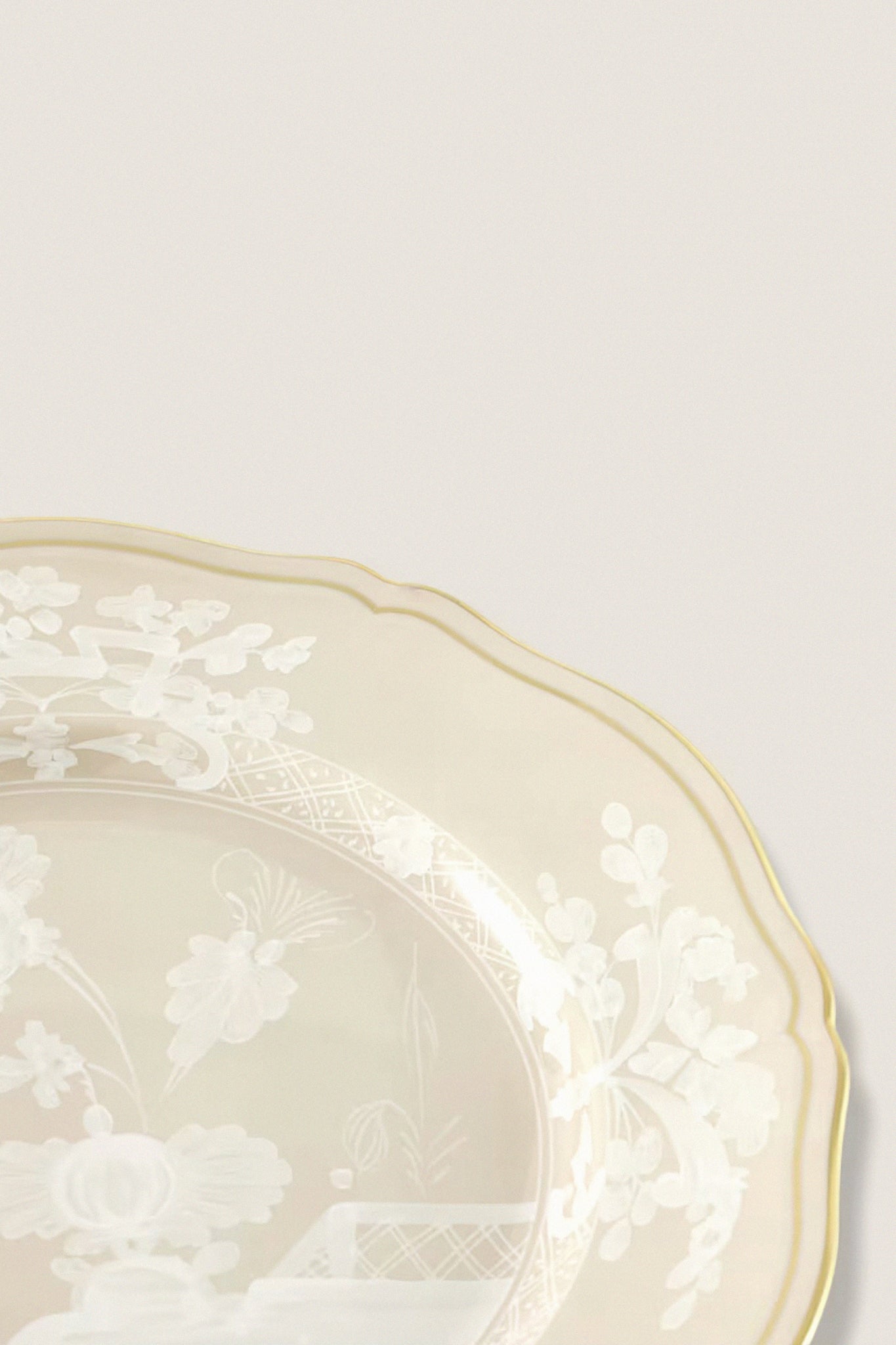 Oriente Italiano Meringa Dinner Plate, a classic porcelain piece with a gold-edged scalloped rim and intricate white floral design, embodies effortless elegance and high-end craftsmanship.
