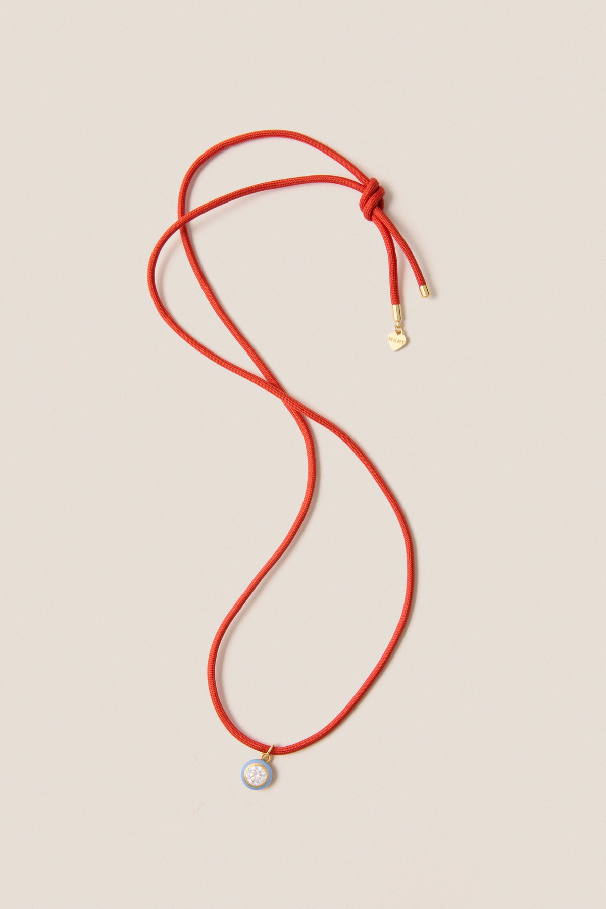 Coral Red Necklace Cord with Blue Bezel Charm, featuring a classic red lariat design with gold accents and a star motif, for effortless, high-end, fun styling.