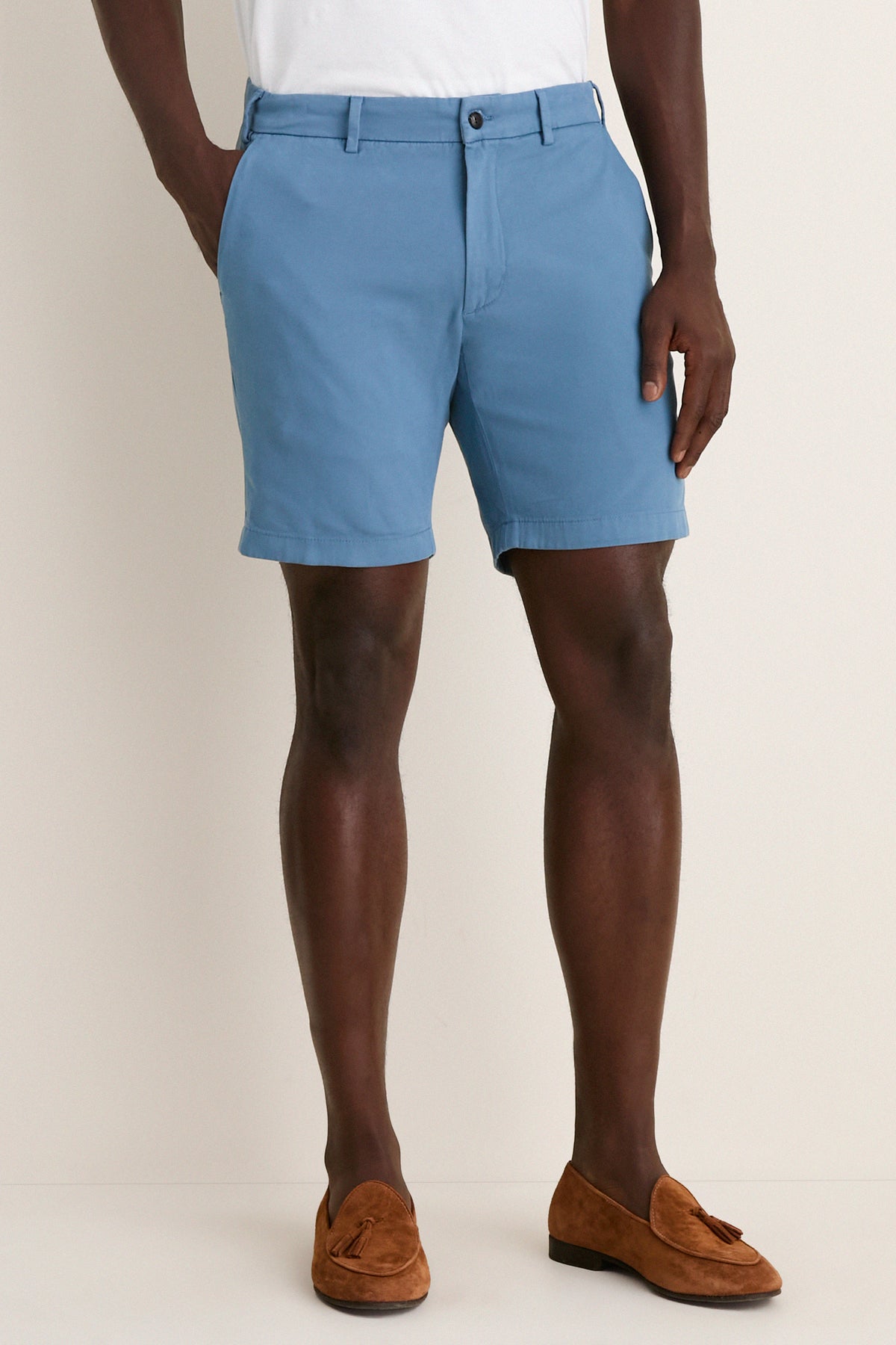 Classic Storm Andrews Flat-Front Short in light blue, worn with white T-shirt and brown loafers. Effortless style for fun, high-end warm-weather adventures.