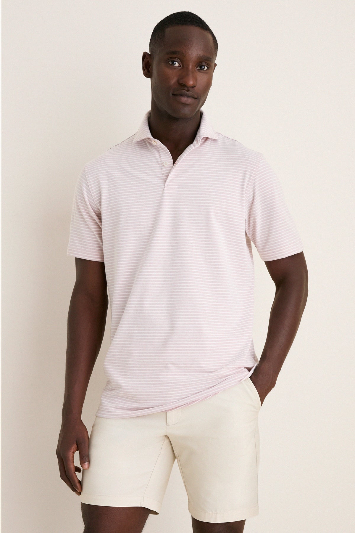 Young man models the classic, high-end Faded Scarlet Stripe Albatross Cotton Blend Pique Polo, exuding effortless style with a fun, relaxed stance.