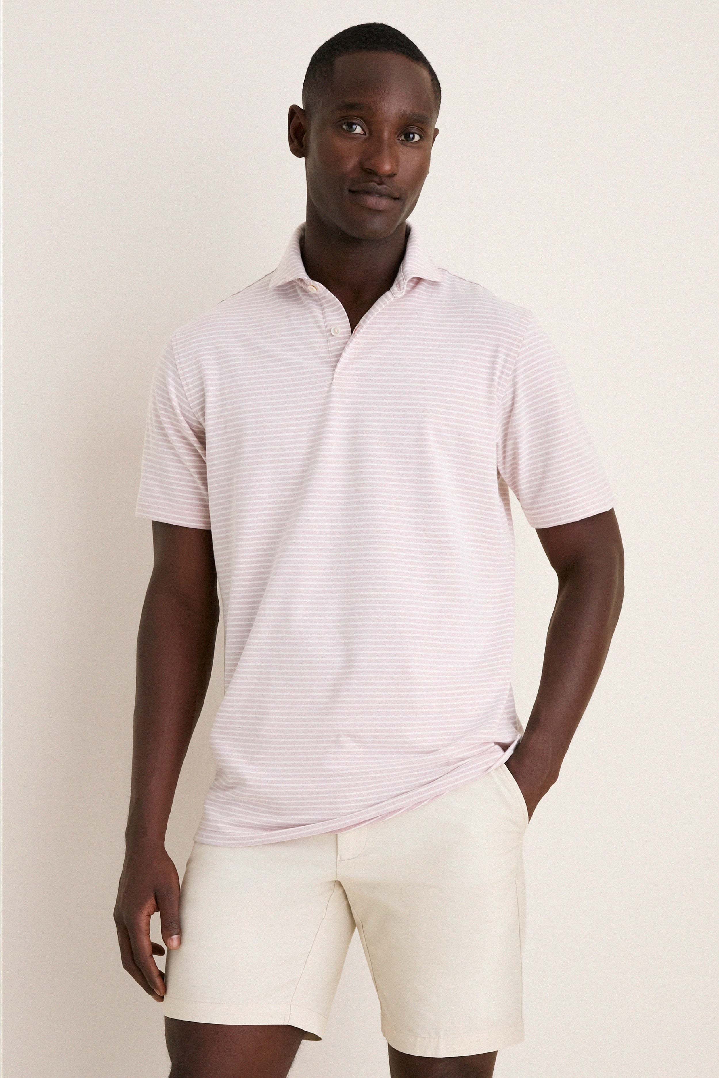 Young man models the classic, high-end Faded Scarlet Stripe Albatross Cotton Blend Pique Polo, exuding effortless style with a fun, relaxed stance.