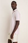 Person in profile wearing Peter Millar's Faded Scarlet Stripe Albatross Cotton Blend Pique Polo, exemplifying classic elegance with a high-end, effortless look featuring mother-of-pearl buttons.