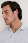 Young man in a classic, light-gray Gale Gray Linen Sanibel Polo, showcasing an effortless, high-end style with its low-profile collar and partial button placket.