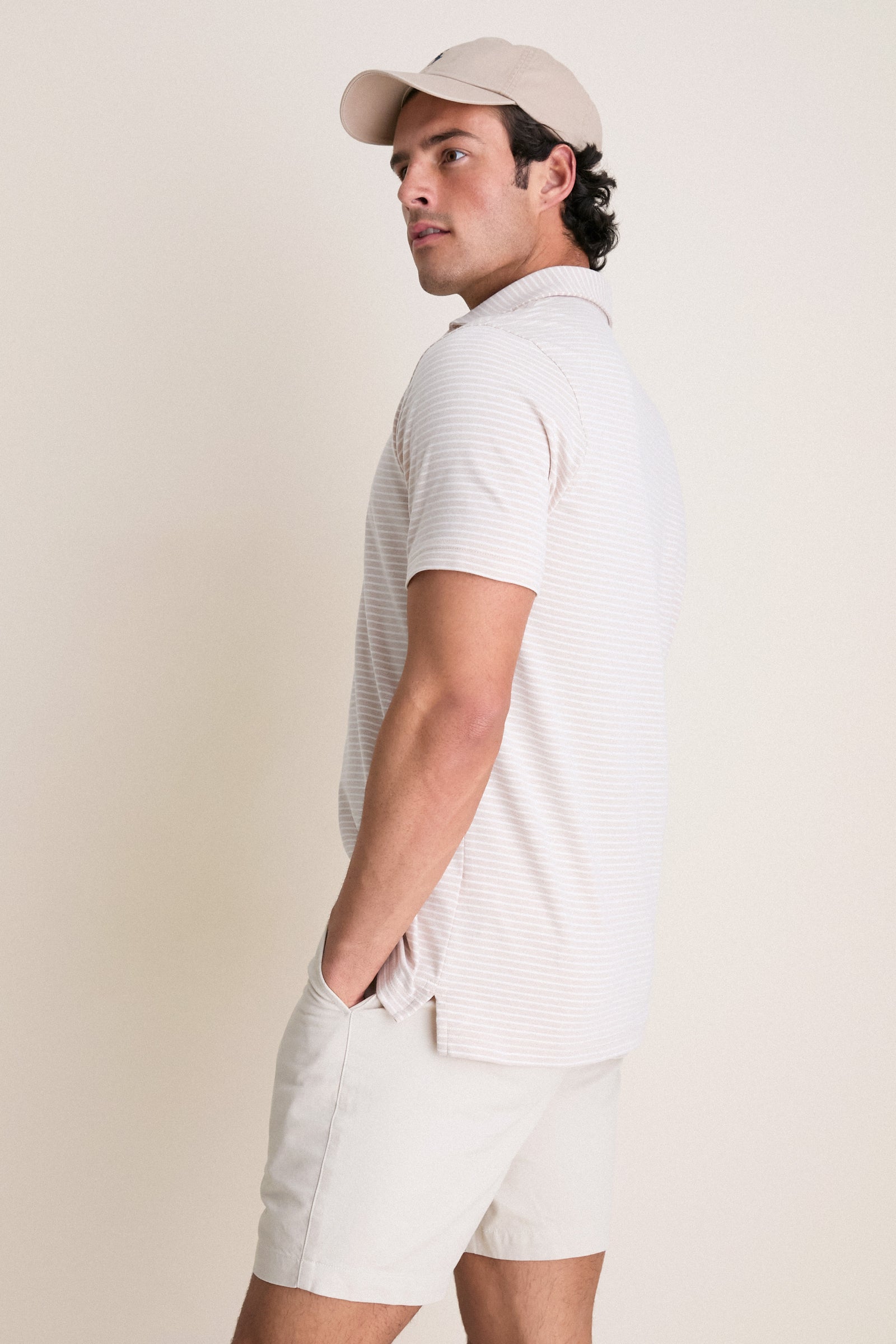 Model in profile wearing the Summer Dunes Stripe Albatross Cotton Blend Pique Polo, showcasing its classic, effortless style with high-end craftsmanship and fun, modern design features.