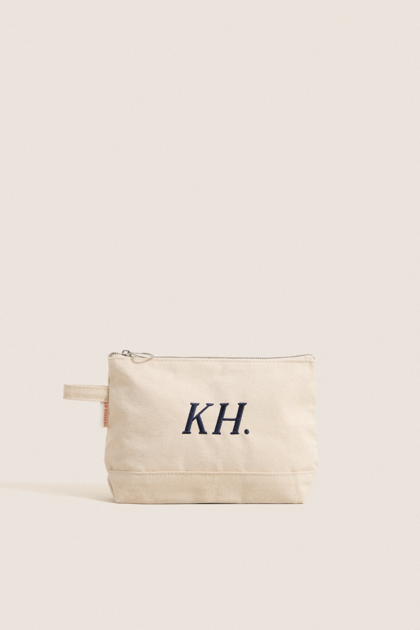 Natural Monogrammed Canvas Make-Up Bag featuring KH initials, classic design with top zip closure and finger loop, offering effortless, high-end functionality for fun, everyday use.
