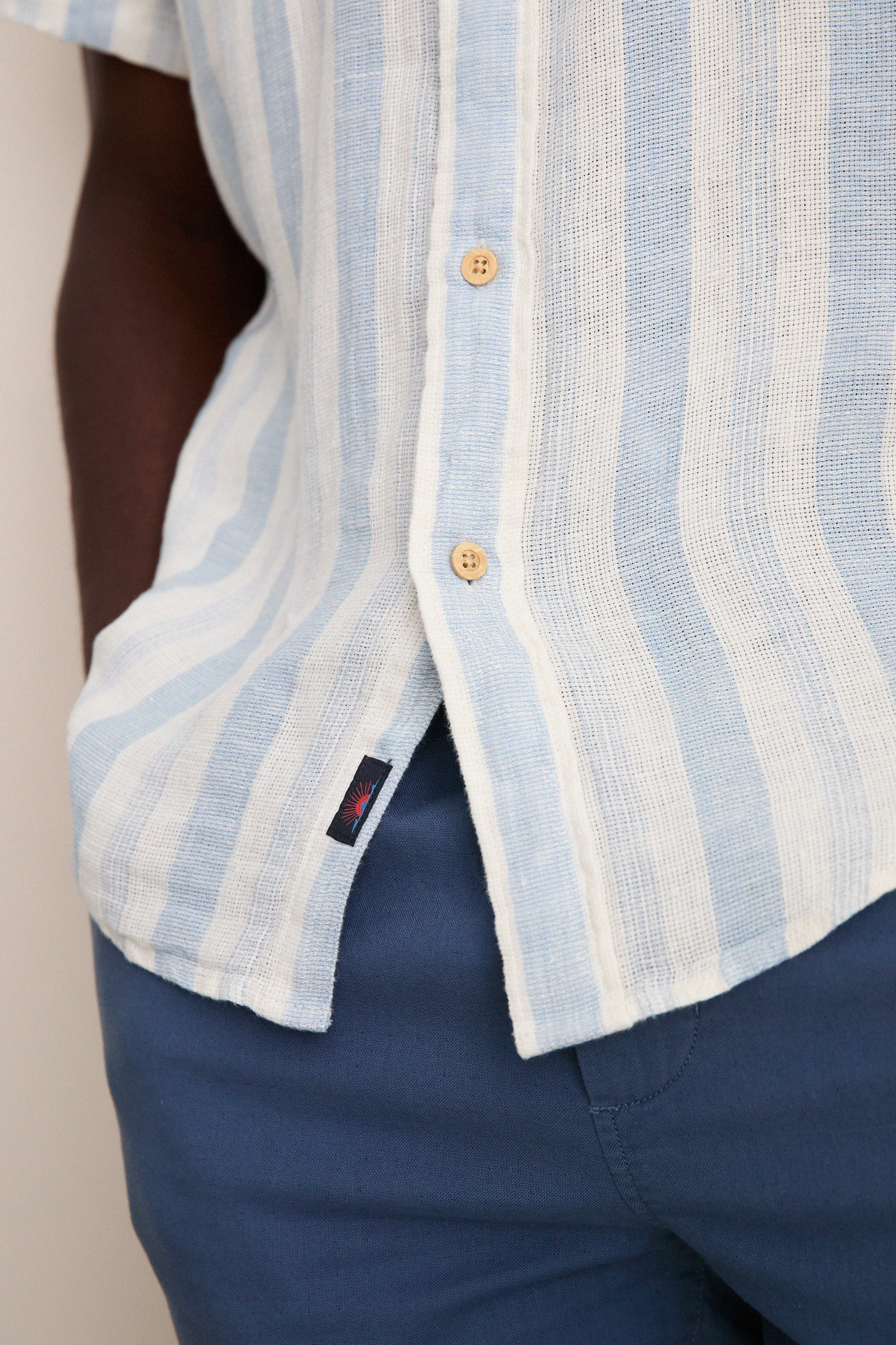 Island Blue Stripe Palma Linen Shirt: A classic, effortless button-down with wooden buttons and a side slit, perfect for fun, high-end warm-weather dressing.