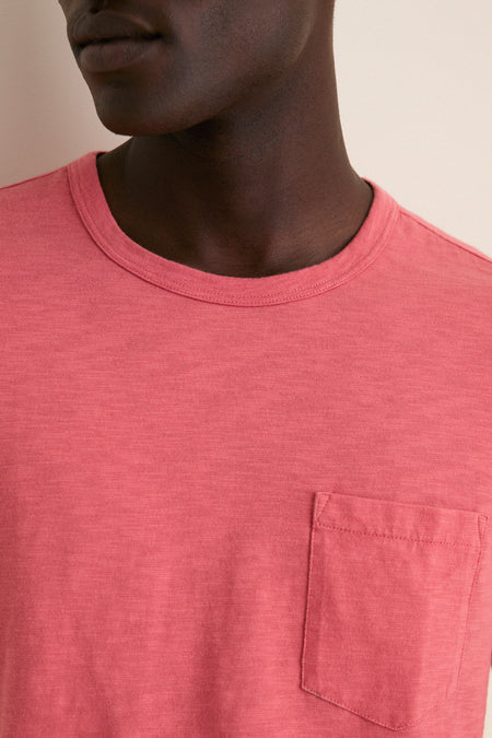 Person wearing a classic Coral Red Sunwashed Pocket Tee with a relaxed fit and chest pocket, embodying an effortless, high-end style for fun, casual adventures.
