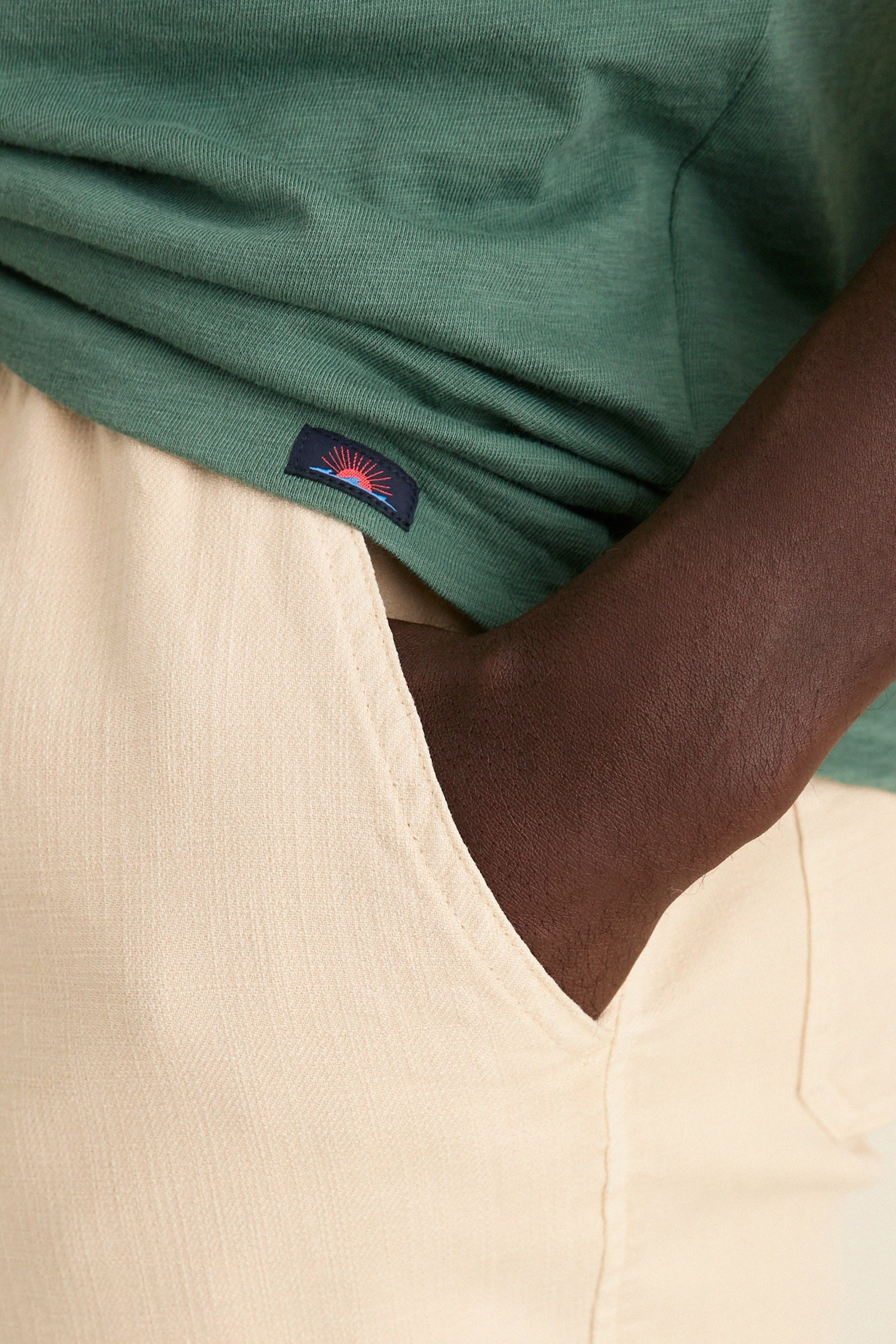 Classic Island Spruce Sunwashed Pocket Tee in forest green, tucked into beige trousers. Effortless style with a high-end feel, showcasing a relaxed fit and soft texture.