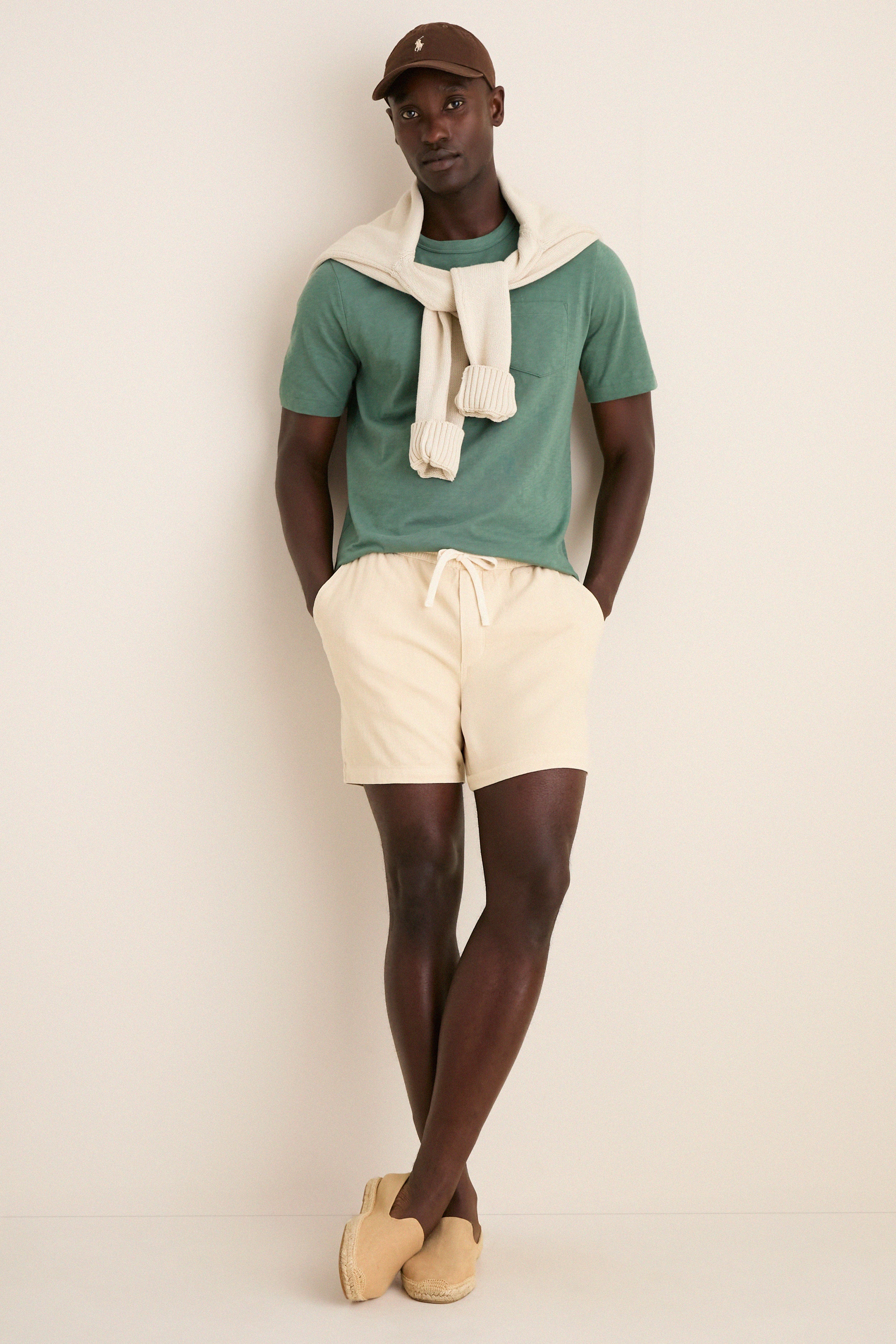 Young man in a classic, sunwashed tee and casual summer attire stands effortlessly, showcasing the high-end Island Spruce Sunwashed Pocket Tee with a relaxed, lived-in feel.