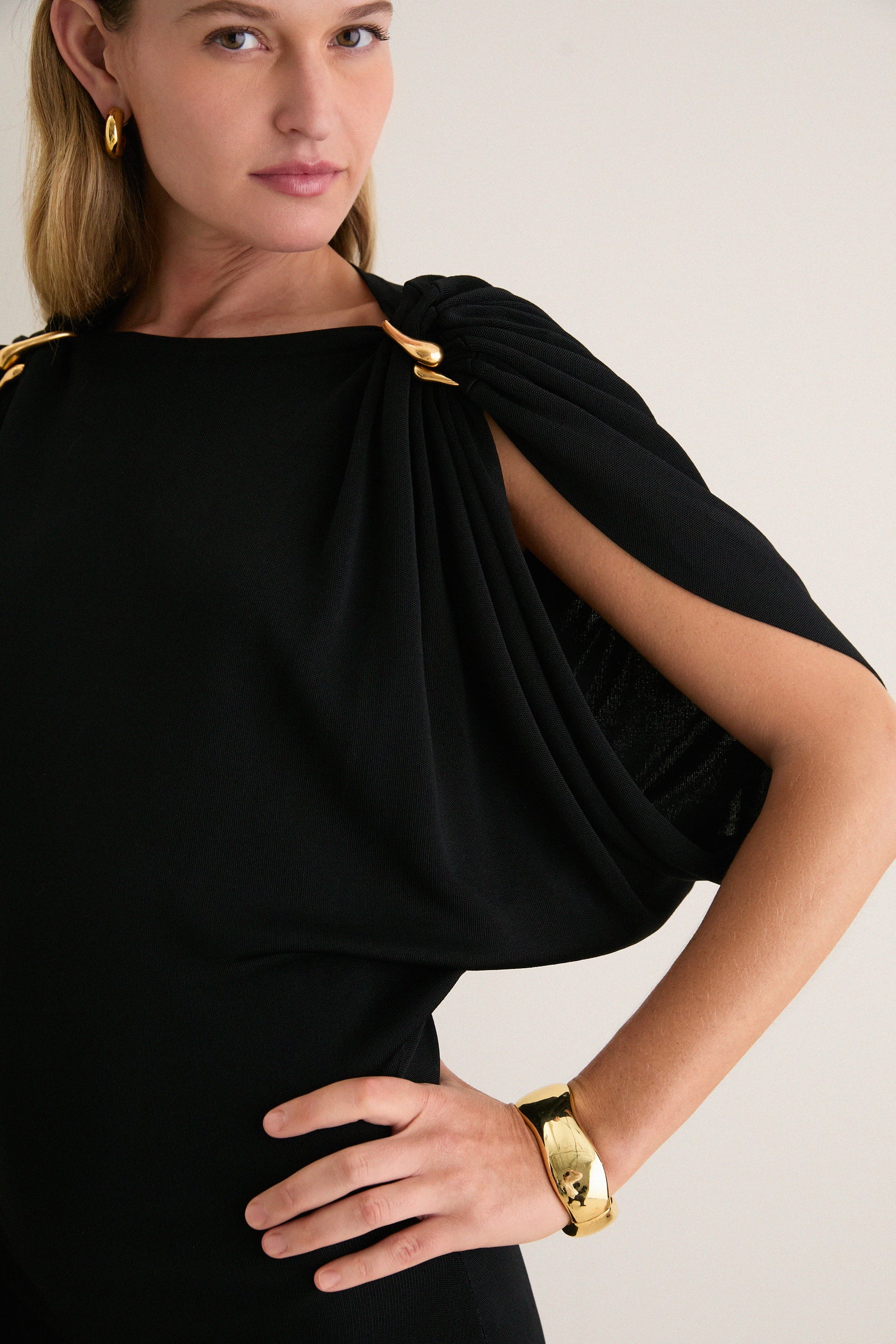 Woman wearing the classic Black Henderson Maxi Dress with an effortless one-shoulder design, featuring sculptural gold clips, a polished gold cuff, and hoop earring for a high-end look.