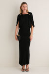 Woman in a classic Black Henderson Maxi Dress with cape sleeves, holding a clutch, accessorized with gold jewelry; an effortless, high-end look for any occasion.