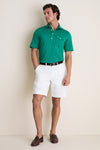 Man wearing the Home Turf Performance Sport Players Shirt, a classic, high-end bright green polo with a 4-button placket and pocket, paired with white shorts. Effortless and fun style.