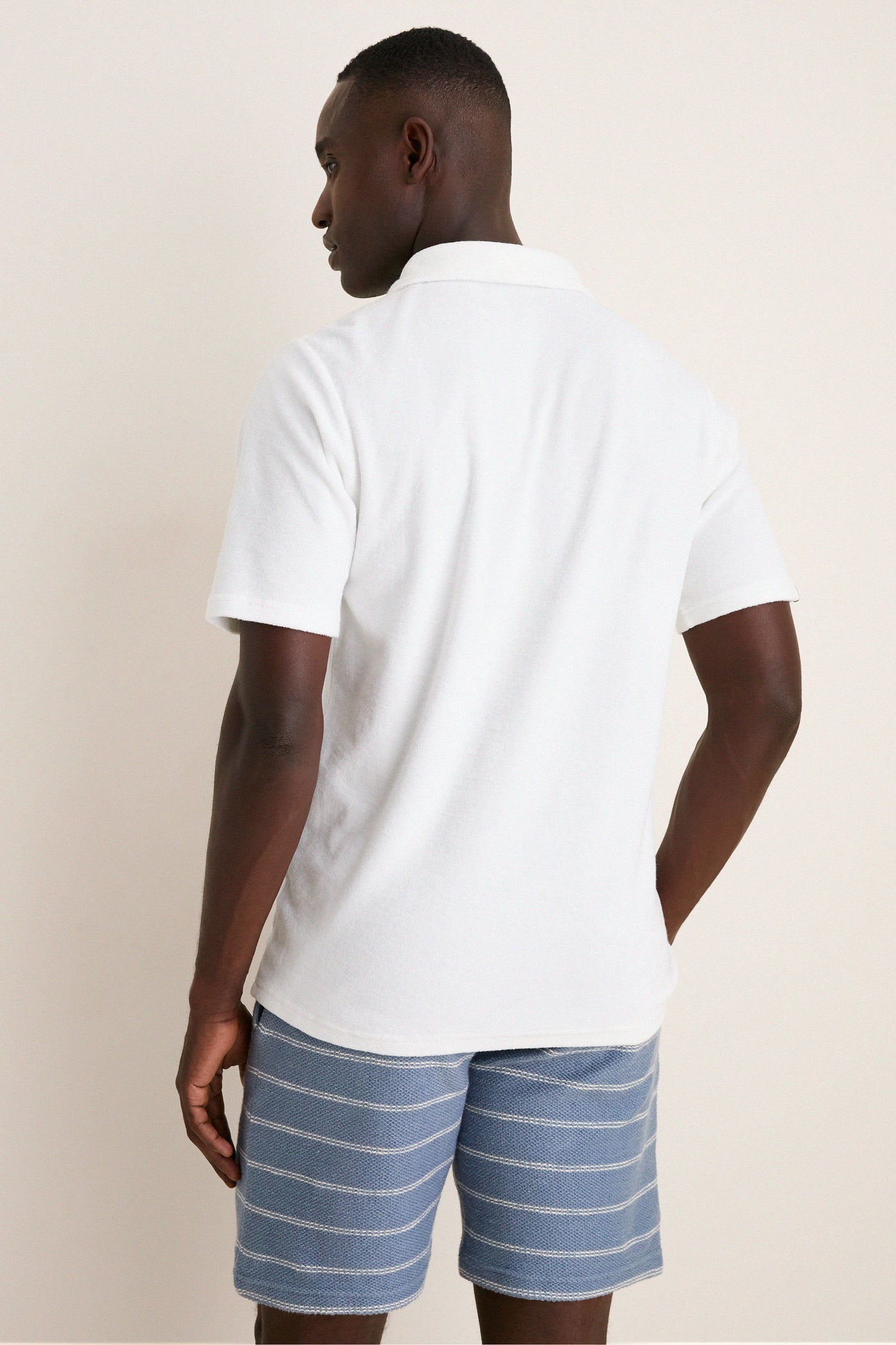 Back view of a man wearing the White Lotus Terrycloth Players Shirt, showcasing its classic style with a flap pocket and four-button placket for an effortlessly cool, high-end look.