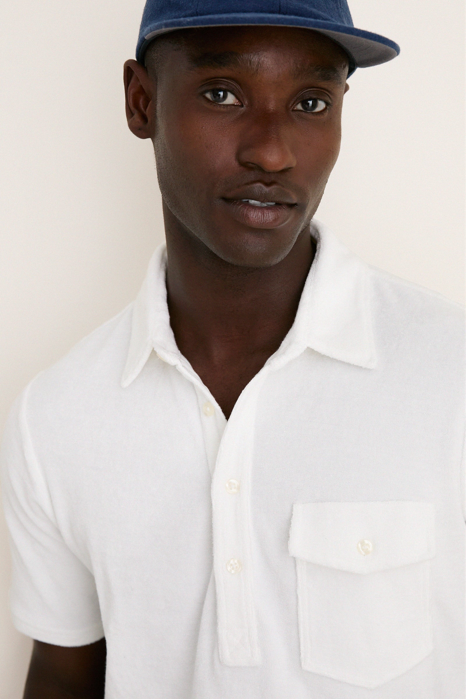 Young man models the classic White Lotus Terrycloth Players Shirt with a 4-button placket, embodying effortless, high-end style perfect for any fun adventure.