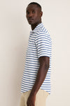 Young man in profile wearing the classic White Performance Pique Knit Button Down with navy stripes and khakis, embodying effortless, high-end style for fun, warm days.