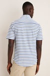 Model in a classic White Performance Pique Knit Button Down, featuring effortless navy-blue stripes and light-beige pants, embodying a high-end, fun style.
