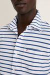 Classic and effortless, the White Performance Pique Knit Button Down features navy stripes, a chest pocket with a red logo, and an open collar for a high-end, fun look.