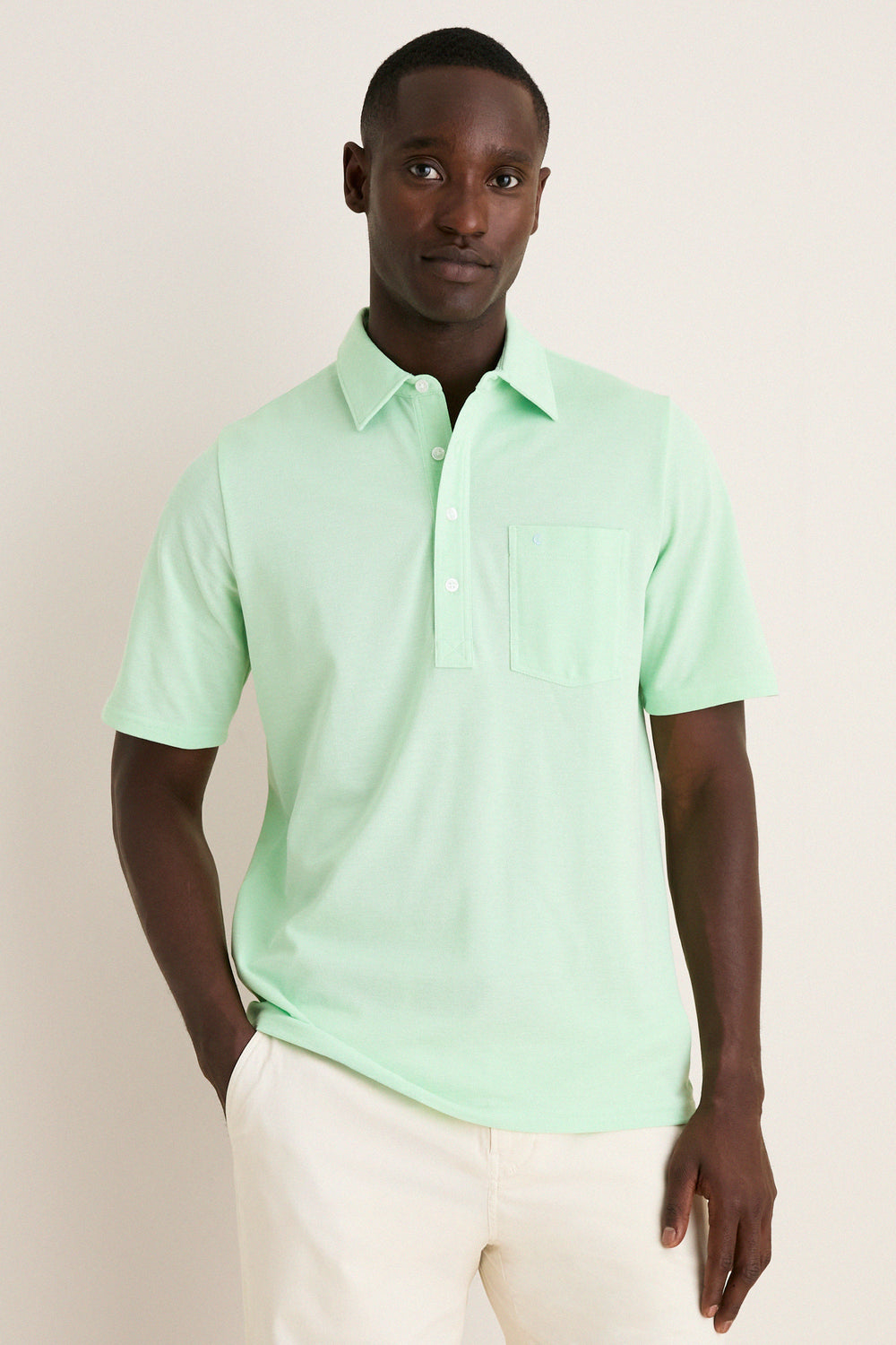 Young Black man wearing the classic Key West Oxford Pique Players Shirt, featuring a spread collar and chest flap pocket, paired effortlessly with trousers for a fun, high-end look.