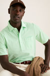 Man wears the classic Key West Oxford Pique Players Shirt, exuding effortless style with its 4-button placket and flap pocket, paired with a casual, high-end look.