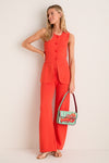 Woman models classic coral-orange outfit with Summer Lobster Tommy Bag featuring a red lobster motif, embodying effortless, fun, high-end style with gold accessories.
