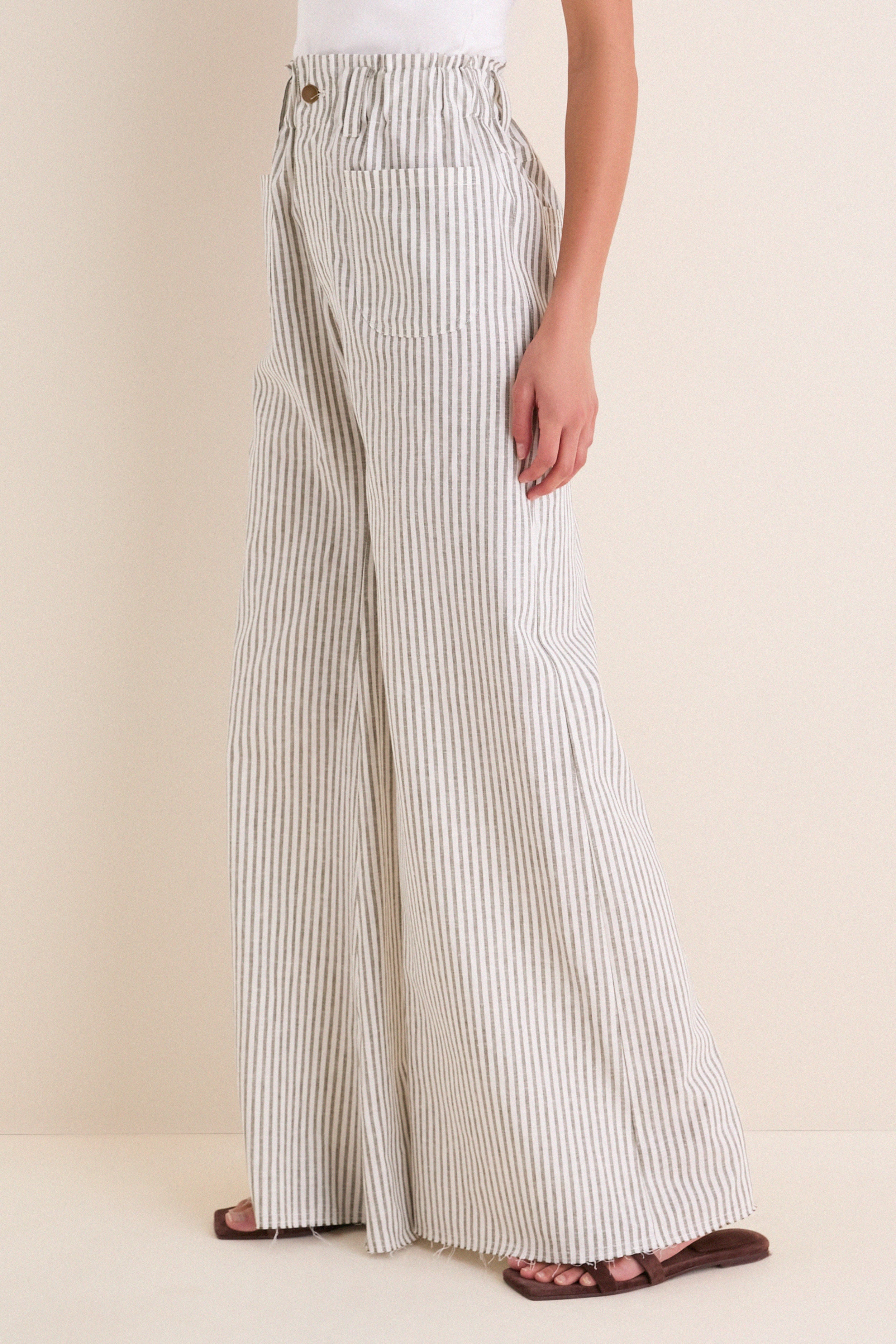Juniper Stripe Linen Tulip Wide Leg Pant: Classic, effortless high-waisted trousers with a relaxed fit, paper-bag waistband, and raw-edge hem, styled with brown sandals for a fun, high-end look.