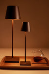 Rust Poldina Pro Table Micro Lamp, classic and cordless, stands elegantly on a tray, embodying effortless high-end design, perfect for fun indoor and outdoor illumination.