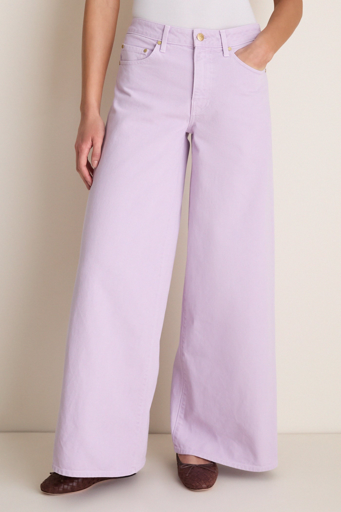 Model wearing Wisteria Zephyr Mid Rise Wide Leg Jean: classic, effortless lavender denim with a flattering fit, showcasing fun, high-end style with front and back pockets.