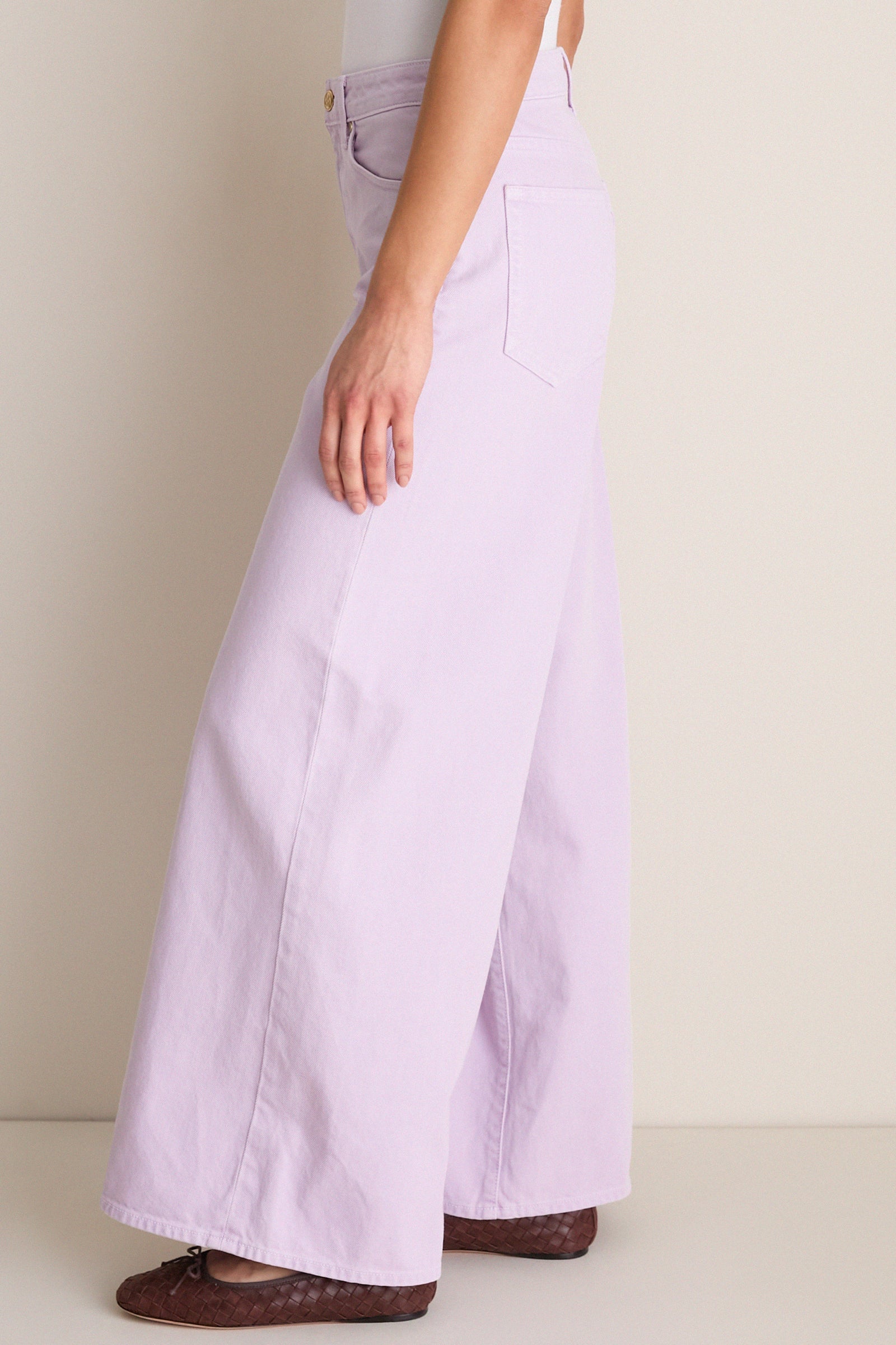 Model wearing Wisteria Zephyr Mid Rise Wide Leg Jean in lavender with a classic high-end look. Effortless style paired with dark brown woven ballet flats.