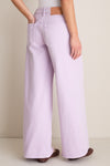 Model wearing Wisteria Zephyr Mid Rise Wide Leg Jean, showcasing classic, effortless style with wide legs, low waist, and patch pockets, paired with woven-leather flats.