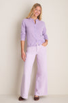 Young woman models the Wisteria Zephyr Mid Rise Wide Leg Jean, effortlessly styled with a lilac cardigan, embodying a classic, high-end, and fun aesthetic.