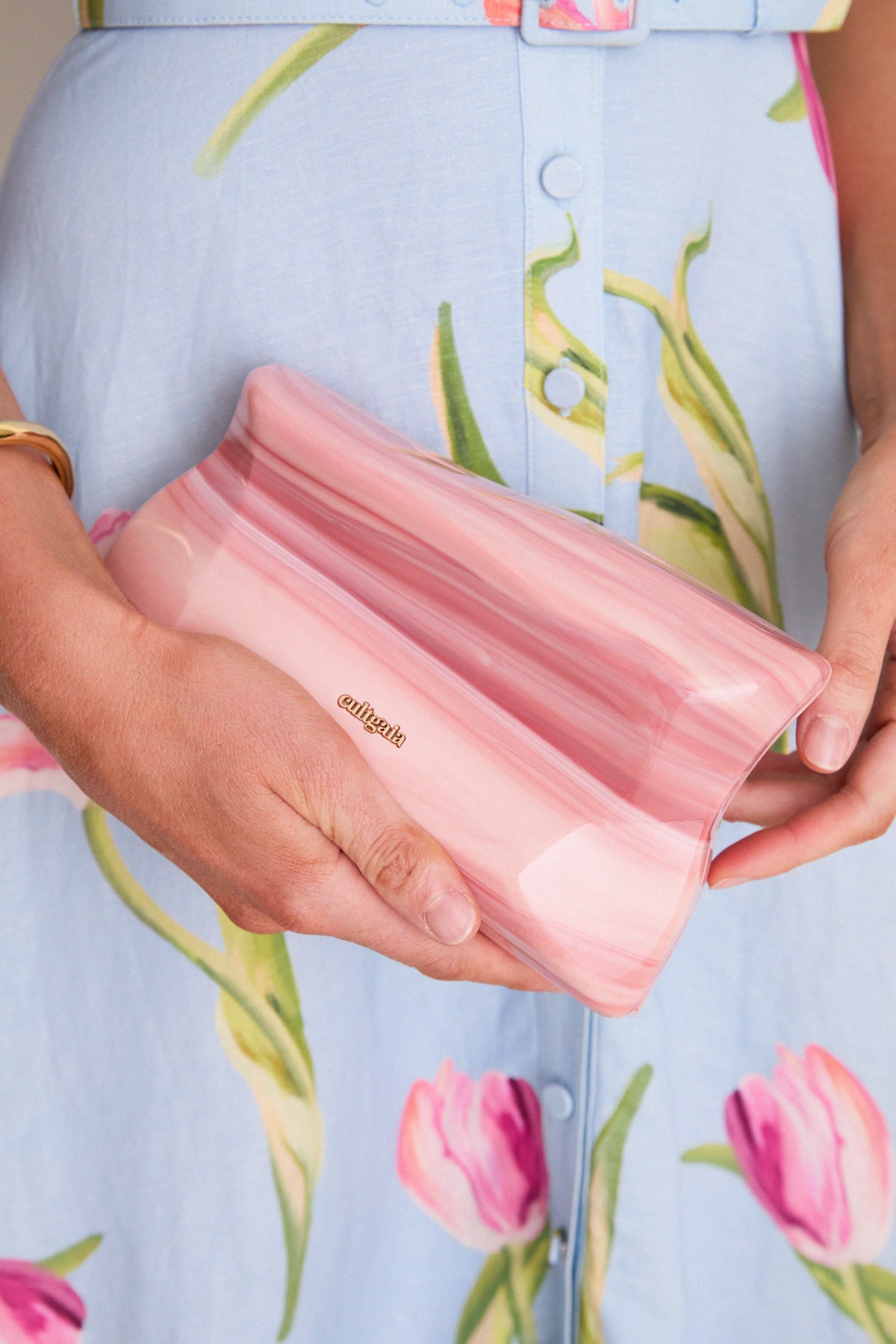 Close-up of Rose Water Malaya Clutch, a classic and sculptural marbled rose acrylic clutch with a gold logo, embodying effortless elegance and high-end design.