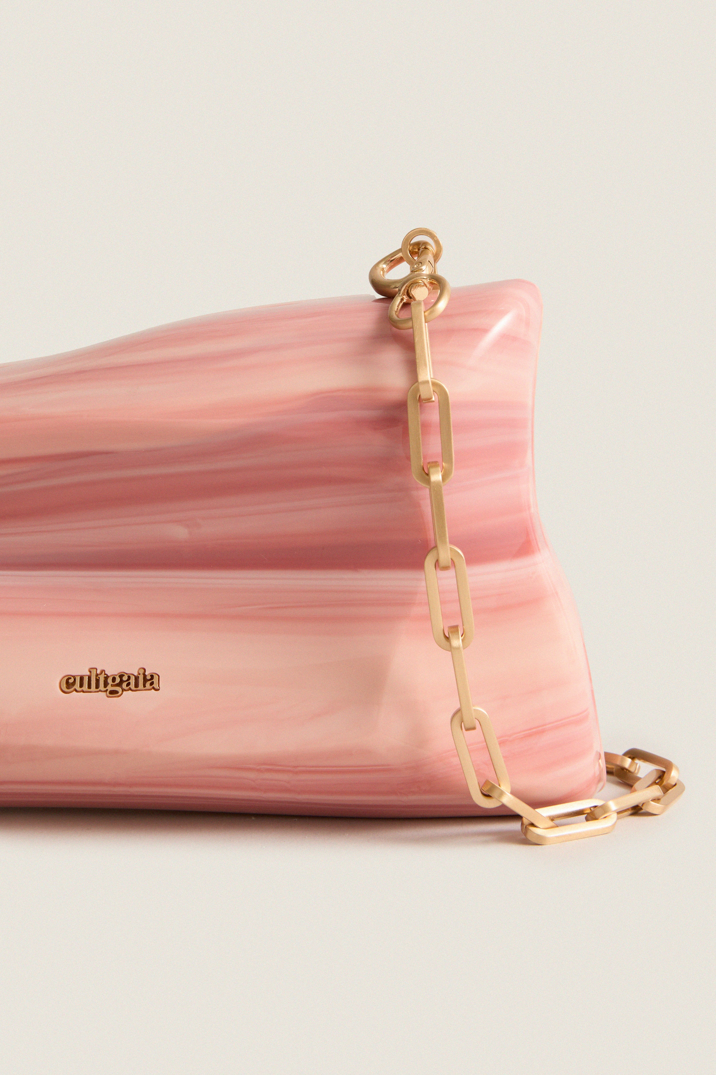 Cult Gaia's Rose Water Malaya Clutch in marbled acrylic, featuring a chunky gold-link chain. Classic, high-end design with an effortless, fun twist.