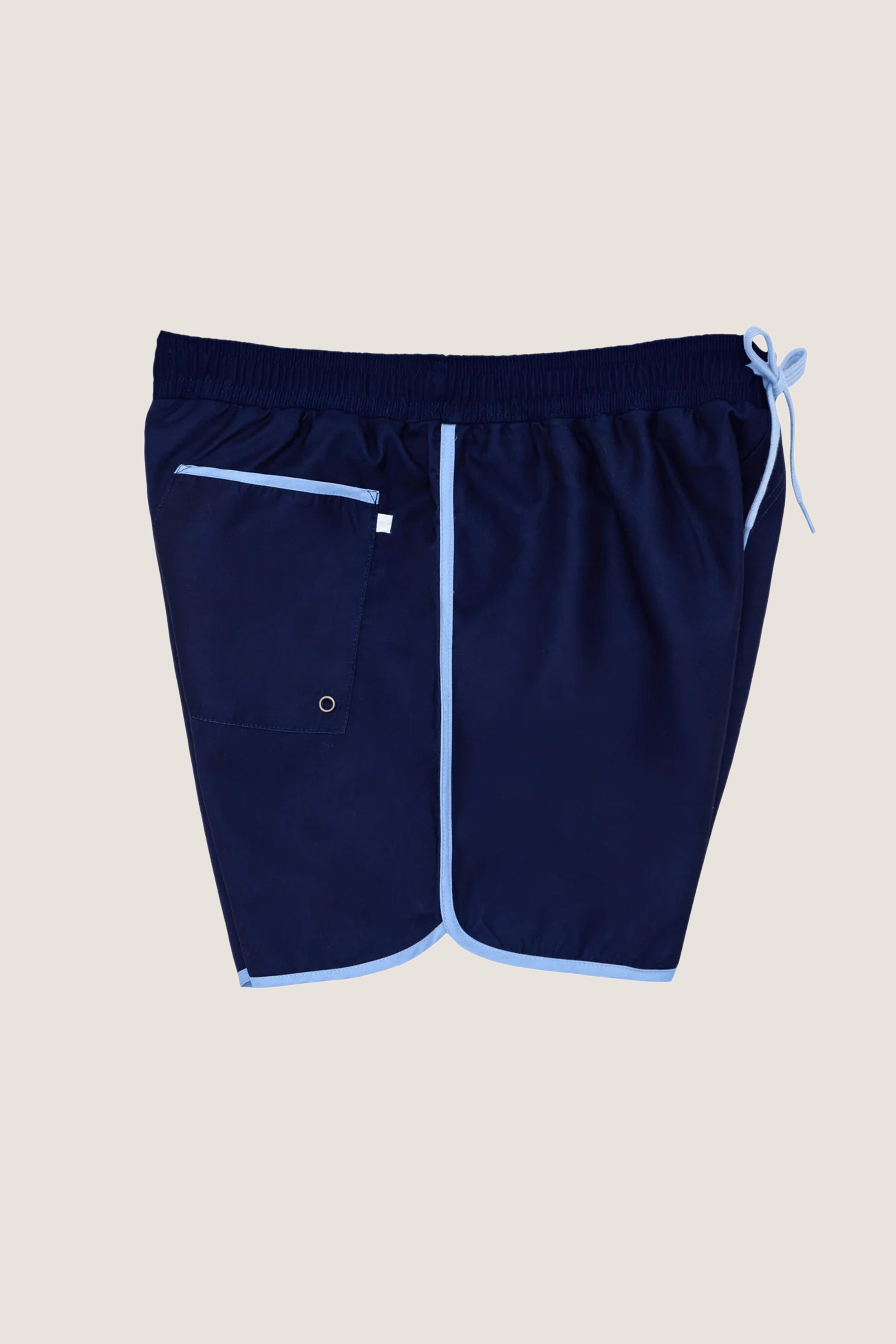 Navy Boardie swim trunks with light-blue trim, featuring an elastic drawstring waist, side pockets, and a back patch pocket, offer a classic, effortless, and fun high-end style.