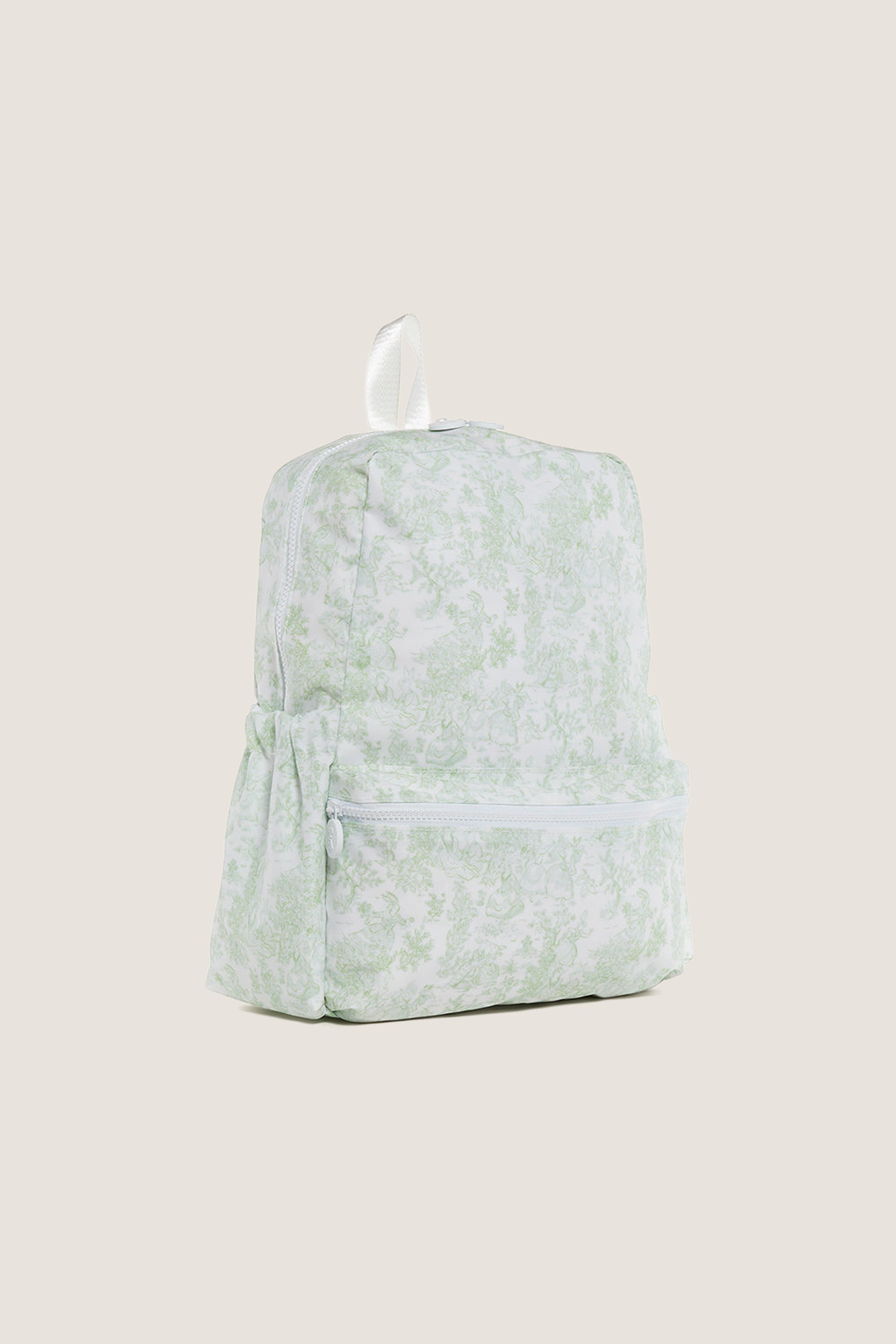 Green Bunny Toile Backpack with classic toile pattern, effortless design featuring a zippered main compartment, front zip pocket, side pockets, and a fun white carry loop.