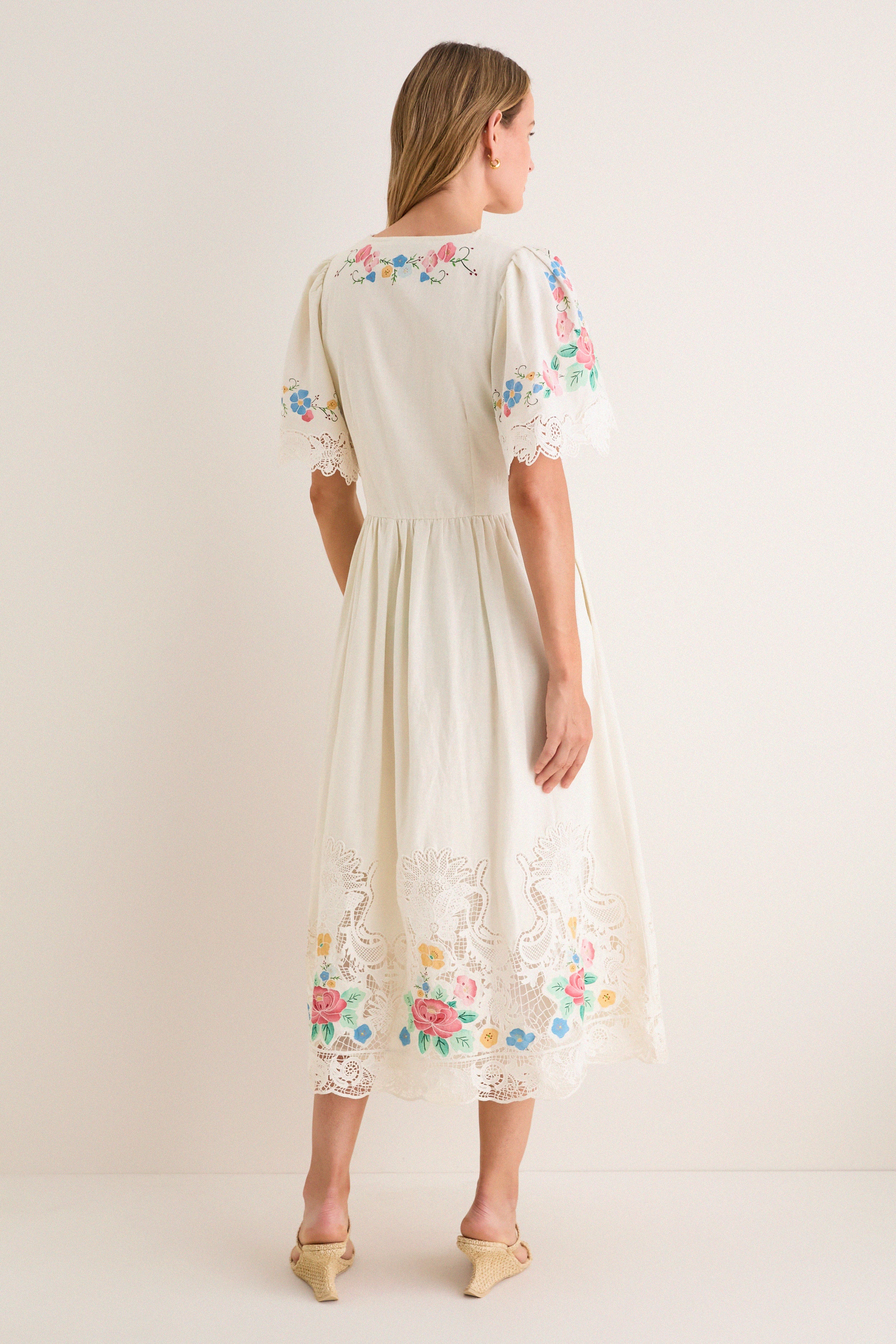 Back view of woman in classic, high-end Multi Astrid Embroidery Short Sleeve Midi Dress with puffed sleeves, colorful embroidery, and gathered skirt, embodying effortless and fun style.