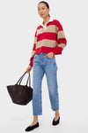 A woman holds a black woven tote bag from Tuckernuck, wearing a ruby striped polo, light blue jeans, and black flats.