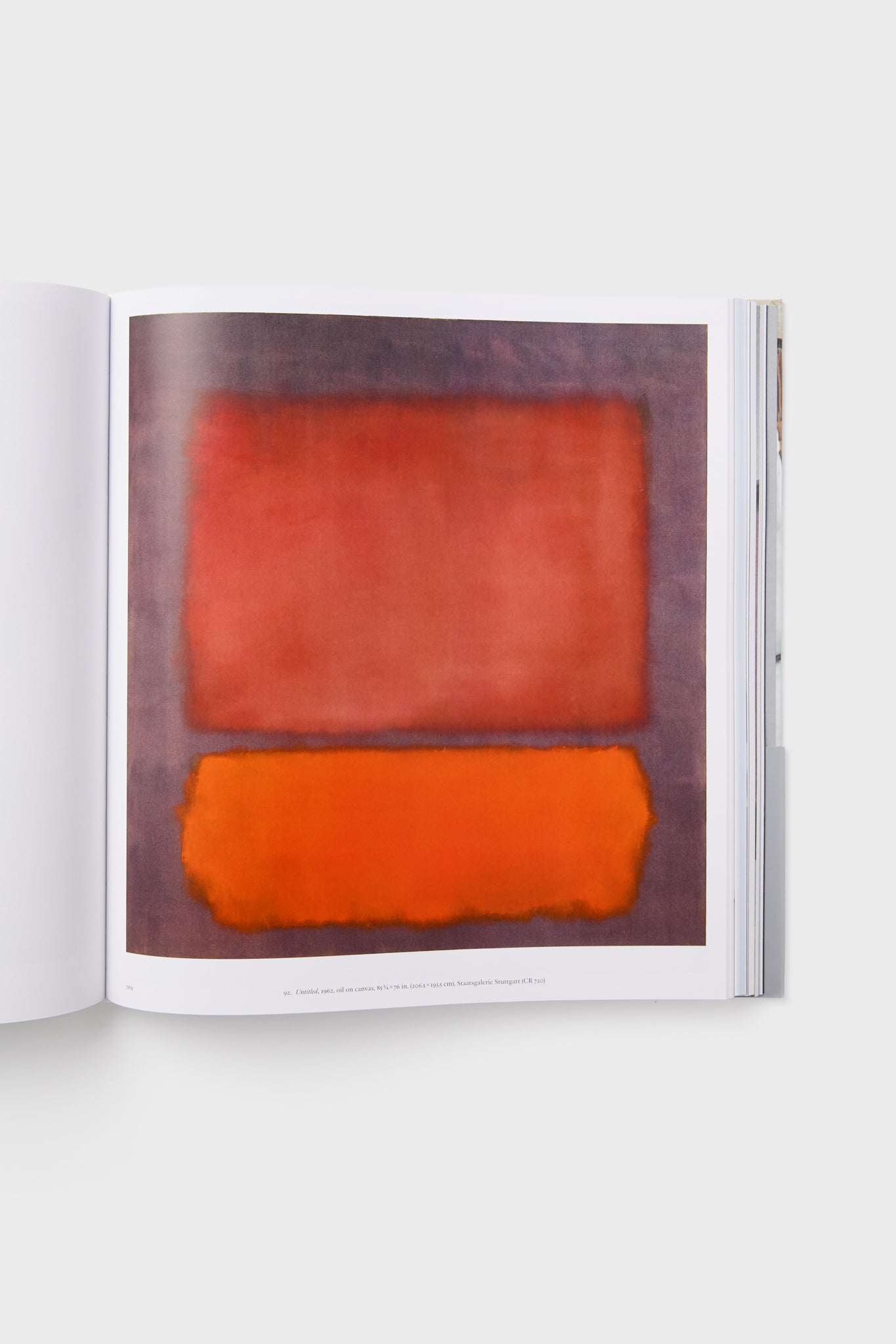 A Harper Group book lies open, showing a page with an abstract painting of two large, blurred red and orange rectangles on a muted background, evoking the style of a Mark Rothko exhibition.