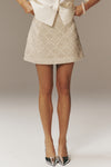 Ivory Sequin Meg Mini Skirt with a classic A-line silhouette and subtle sparkle, paired effortlessly with metallic heels for a fun, high-end look.