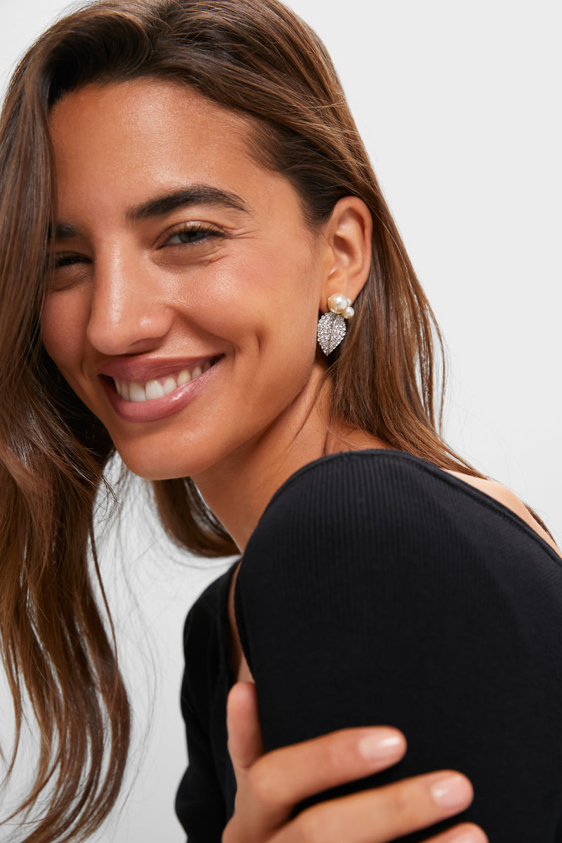 Young woman in a fitted black top showcases classic Crystal Pearl Blanca Earrings, featuring pearl studs and crystal-embellished leaf drops, exuding effortless, high-end charm.