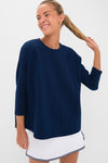 Young woman models the Navy Cable Ally Swing Sweatshirt with three-quarter sleeves, showcasing its classic, effortless style paired with a fun, high-end tennis skirt.