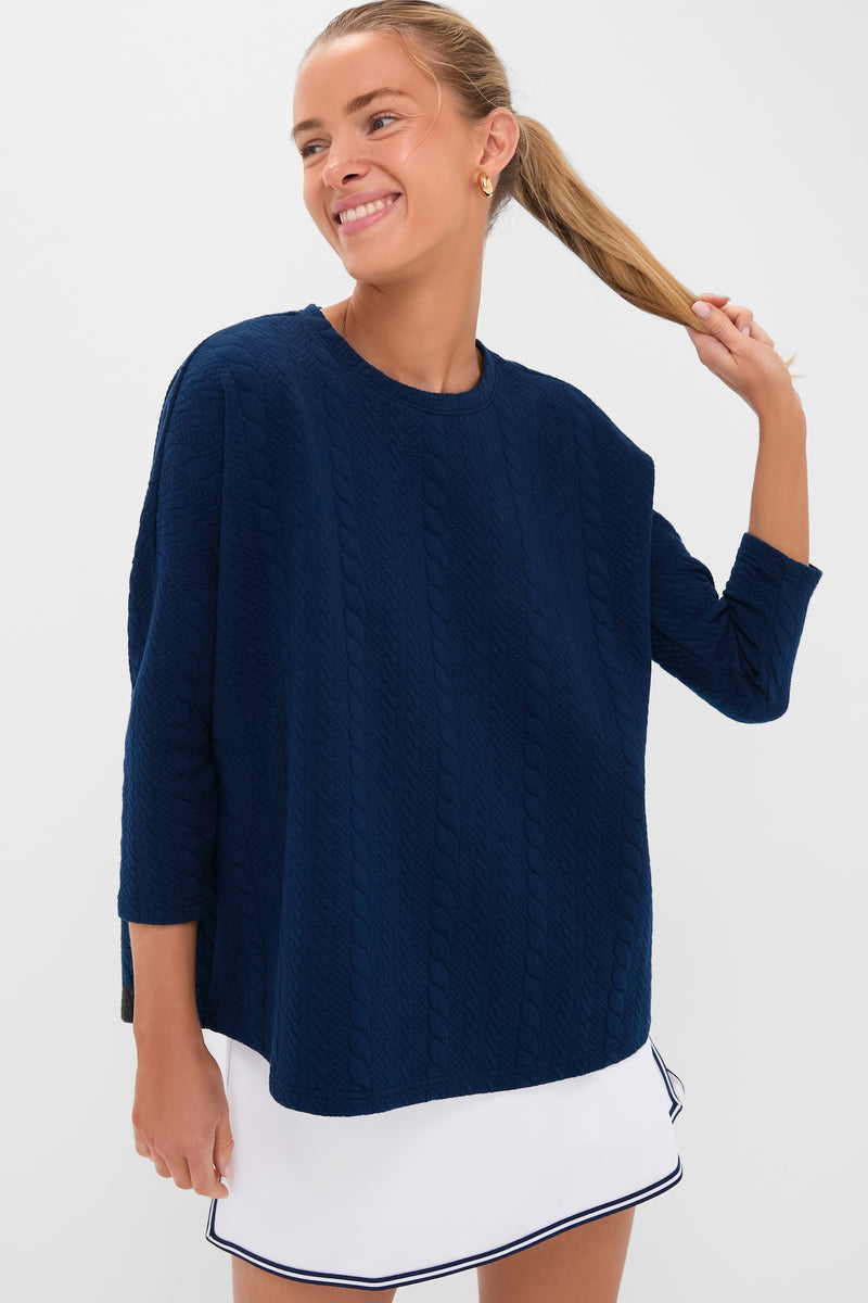 Young woman models the Navy Cable Ally Swing Sweatshirt with three-quarter sleeves, showcasing its classic, effortless style paired with a fun, high-end tennis skirt.