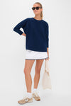 Woman wearing Navy Cable Ally Swing Sweatshirt with quilted texture, loose fit, and relaxed drop shoulders, paired effortlessly with a white skirt and sneakers, exuding classic, high-end style.