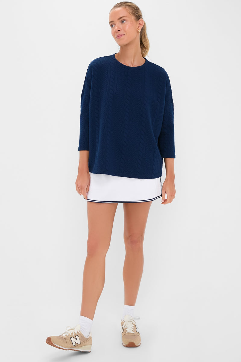 Woman wearing the classic Navy Cable Ally Swing Sweatshirt with three-quarter sleeves, paired with a white skirt, embodying an effortless, fun, and high-end style.