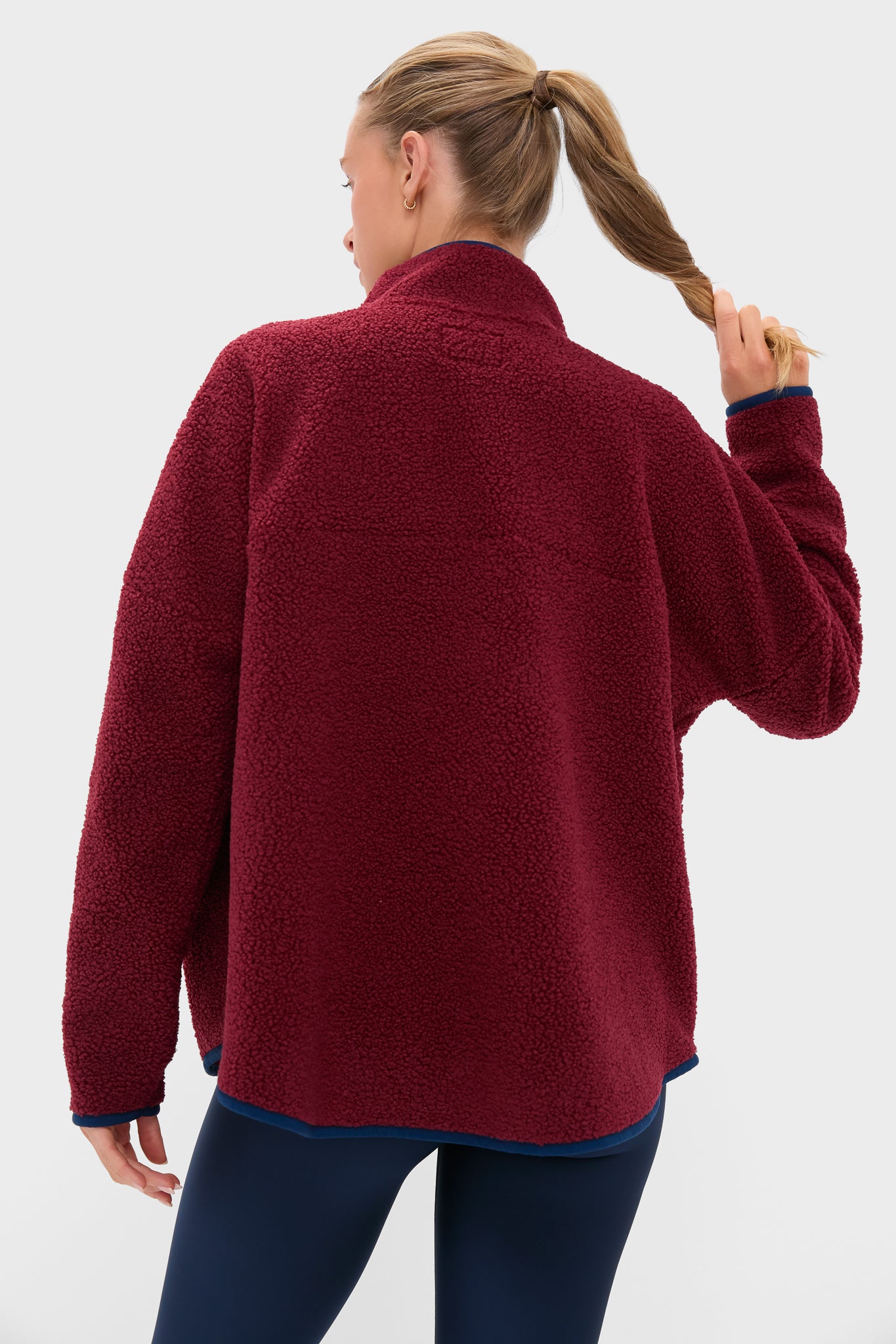 Woman in Cabernet Fleece Cady Quarter Zip with contrasting trim and navy leggings, exuding a classic, effortless style—perfect for high-end, fun, and versatile wear.