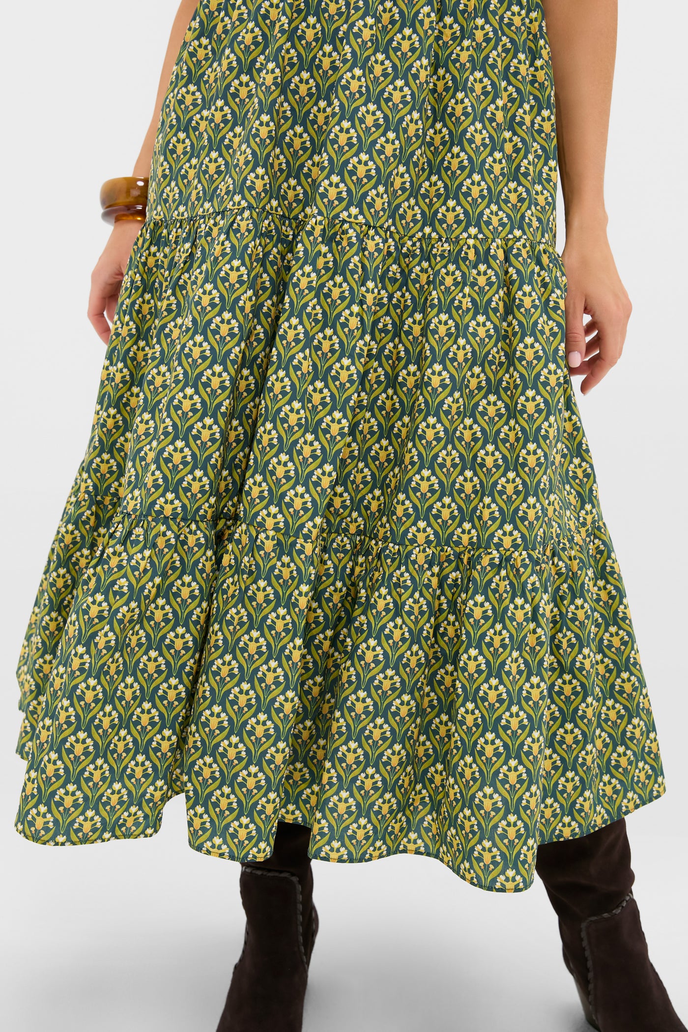 Forest Green Floral Bennett Maxi Dress showcasing a tiered midi skirt with yellow floral print, paired with dark boots and an amber bangle for a classic, effortless, high-end look.